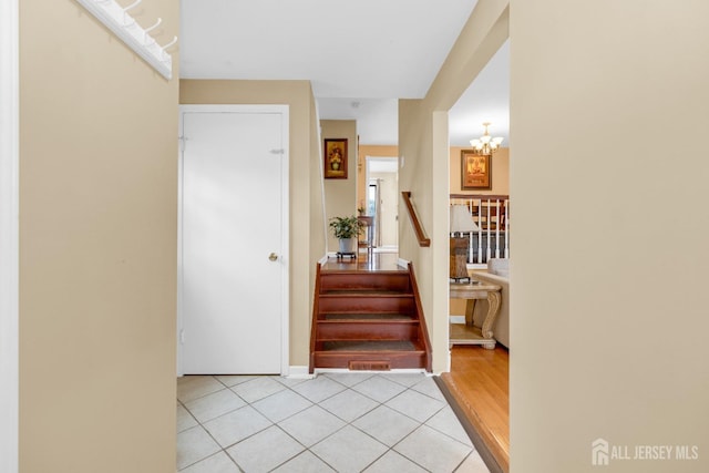 entrance foyer with stairway, a notable chandelier, and light tile patterned flooring
