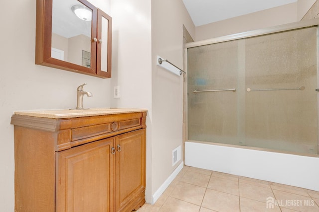 bathroom with vanity, combined bath / shower with glass door, visible vents, baseboards, and tile patterned flooring