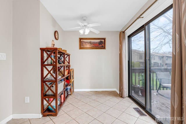 empty room featuring light tile patterned floors, a ceiling fan, visible vents, and baseboards