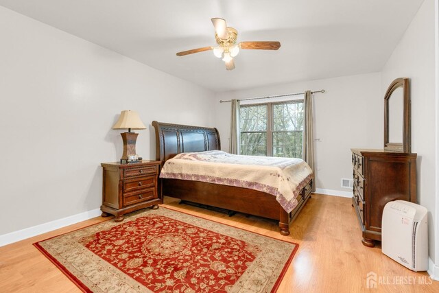 bedroom with baseboards, ceiling fan, and light wood-style flooring