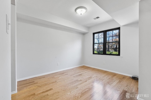 unfurnished room with baseboards, light wood finished floors, and visible vents