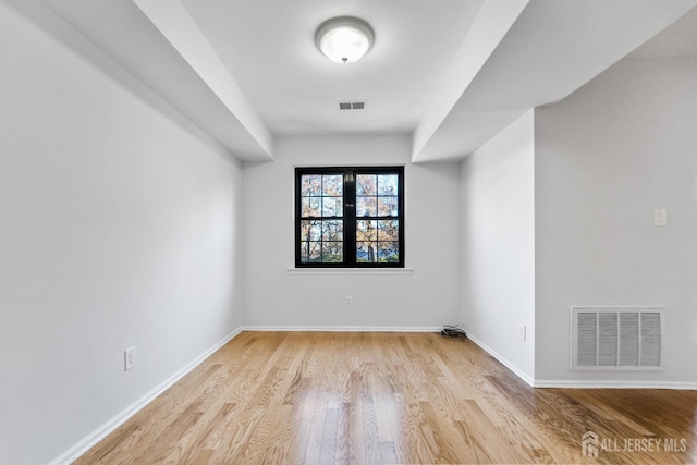 empty room with visible vents, light wood-style floors, and baseboards