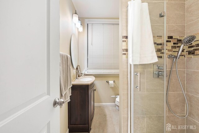 bathroom featuring vanity, a shower with shower door, tile patterned flooring, and toilet