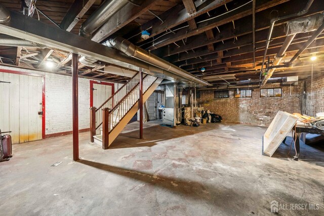 basement featuring brick wall and heating unit