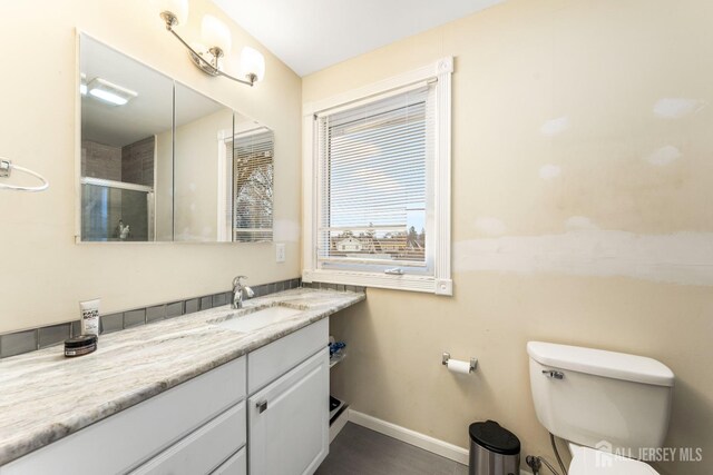 bathroom featuring a shower with shower door, toilet, and vanity