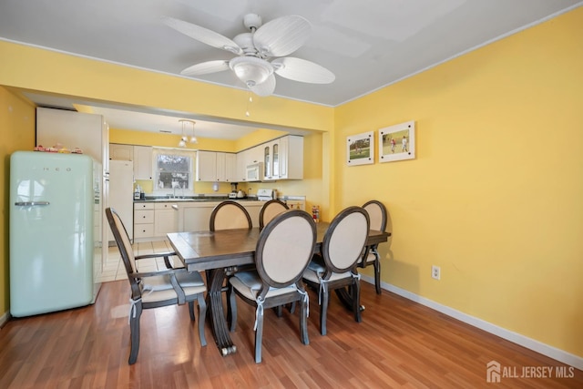 dining area with baseboards, wood finished floors, and a ceiling fan