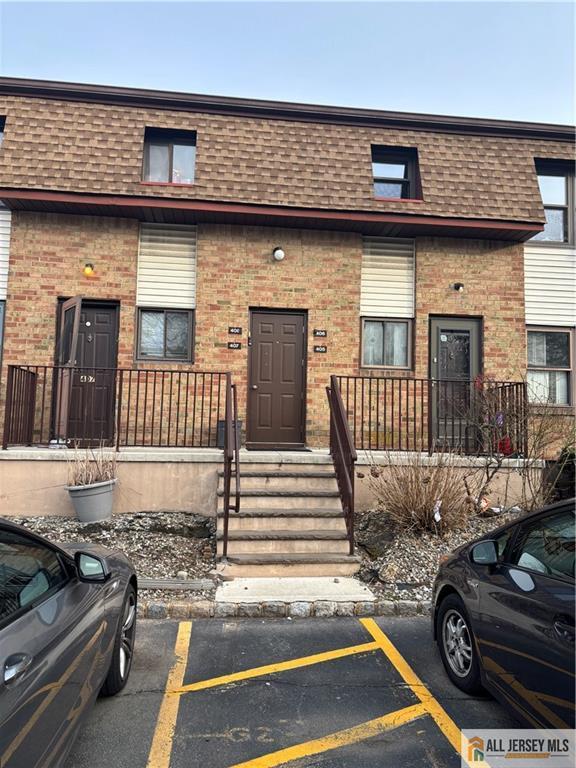 townhome / multi-family property featuring brick siding, a shingled roof, and mansard roof