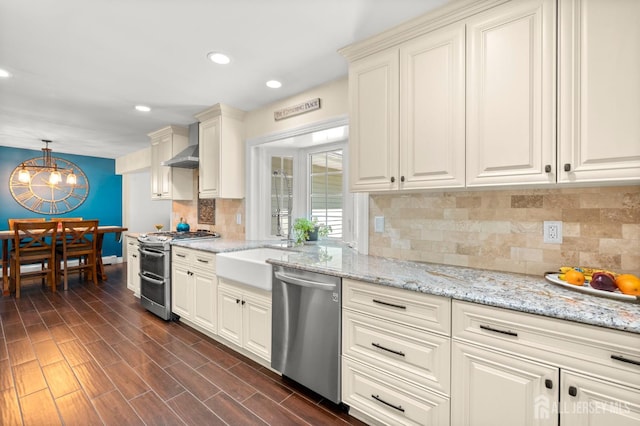 13 Orchard Pkwy, Morganville, NJ 07751 - kitchen featuring stainless steel appliances, a chandelier, wall chimney range hood, light stone countertops, and recessed lighting