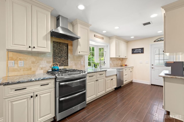 13 Orchard Pkwy, Morganville, NJ 07751 - kitchen with appliances with stainless steel finishes, wall chimney exhaust hood, tasteful backsplash, light stone countertops, and dark wood-style flooring