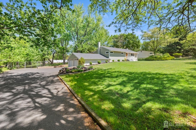 13 Orchard Pkwy, Morganville, NJ 07751 - view of front of house featuring asphalt driveway, a front yard, an attached garage, and view of wooded area