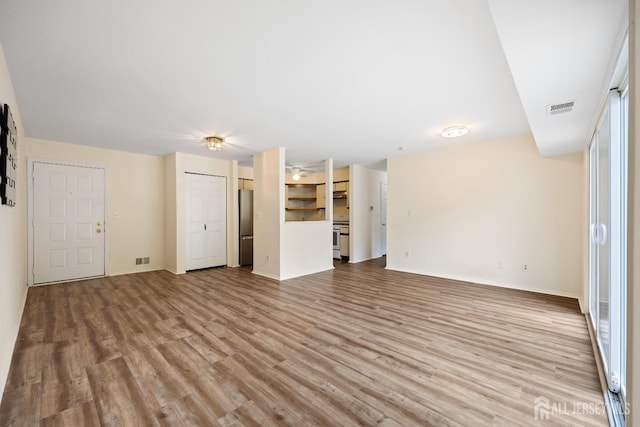 unfurnished living room featuring light wood finished floors, baseboards, and visible vents