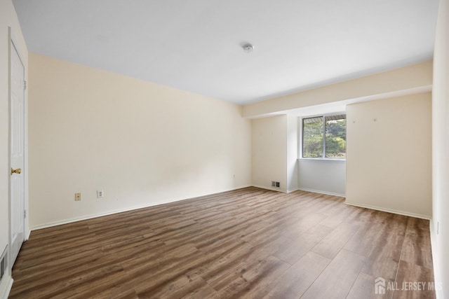 empty room with wood finished floors and visible vents