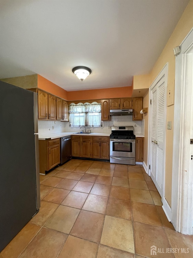 1211 S 9th St, South Plainfield, NJ 07080 - kitchen featuring appliances with stainless steel finishes, under cabinet range hood, light countertops, brown cabinetry, and a sink