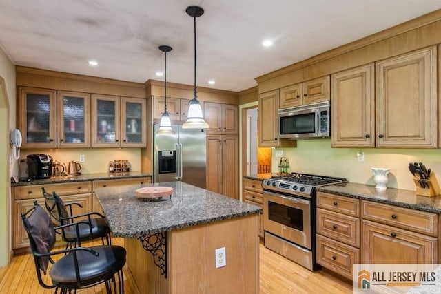 57 Jensen St, East Brunswick, NJ 08816 - kitchen featuring stainless steel appliances, a kitchen breakfast bar, light wood finished floors, a center island, and dark stone counters