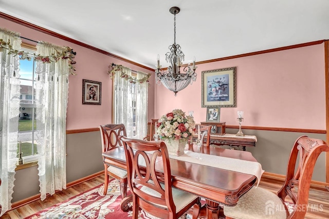 dining area with a chandelier, wood finished floors, ornamental molding, and baseboards