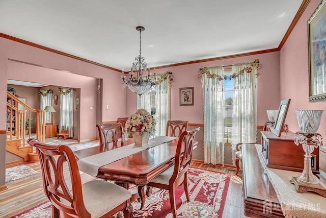 dining space featuring a chandelier, stairs, light wood-type flooring, and crown molding