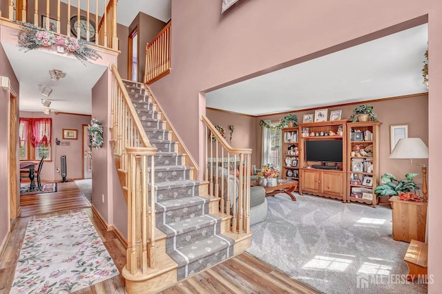 staircase featuring wood finished floors and crown molding