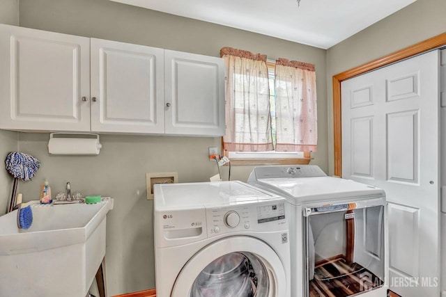 clothes washing area featuring cabinet space and washer and clothes dryer