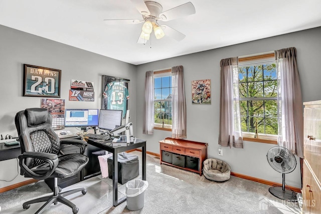 carpeted office featuring baseboards and a ceiling fan