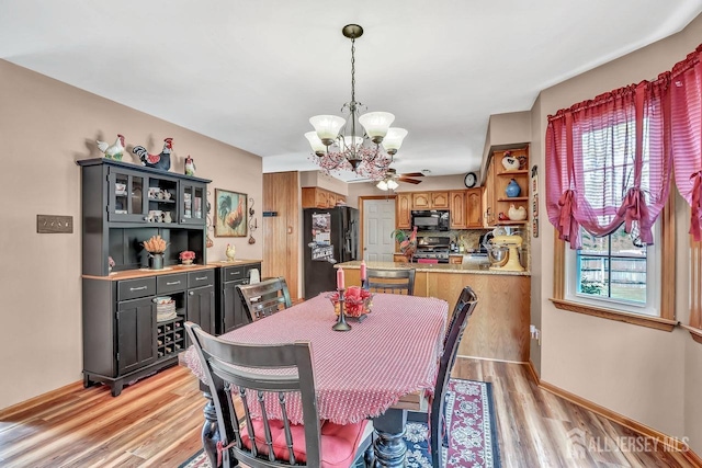 dining space with a chandelier, light wood-type flooring, and baseboards