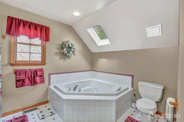 bathroom featuring a skylight, toilet, baseboards, a garden tub, and lofted ceiling