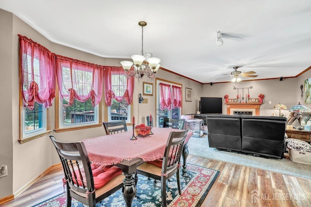 dining space featuring a chandelier, a ceiling fan, light wood-style flooring, crown molding, and baseboards