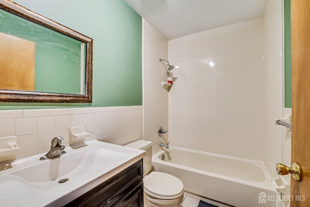 full bathroom featuring toilet, vanity, tile walls, and washtub / shower combination