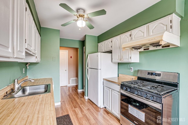 kitchen with white cabinetry, white fridge, stainless steel gas stove, sink, and ceiling fan