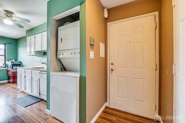 washroom with light wood-type flooring, ceiling fan, stacked washer and clothes dryer, and sink