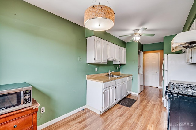 kitchen featuring range with gas stovetop, decorative light fixtures, white cabinetry, sink, and ceiling fan