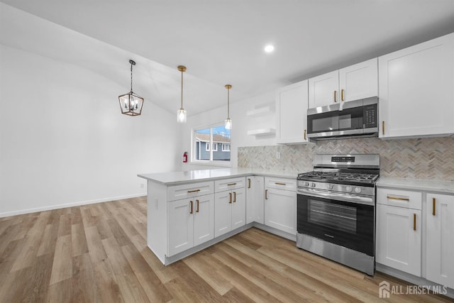 kitchen featuring decorative light fixtures, stainless steel appliances, kitchen peninsula, and white cabinets