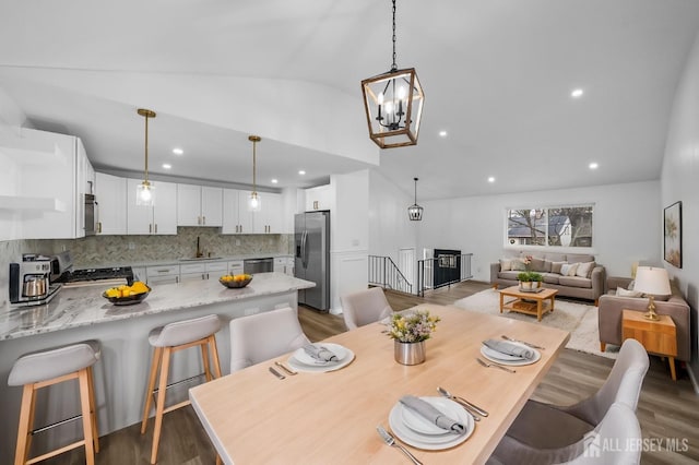 dining area featuring lofted ceiling, sink, wood-type flooring, and a chandelier