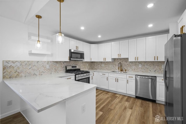 kitchen with appliances with stainless steel finishes, pendant lighting, white cabinetry, sink, and kitchen peninsula