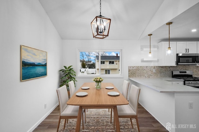 dining area with lofted ceiling, dark hardwood / wood-style floors, and a notable chandelier