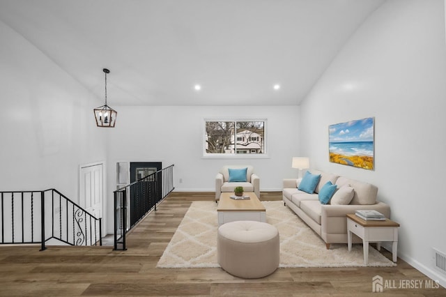 living room with an inviting chandelier, vaulted ceiling, and hardwood / wood-style floors