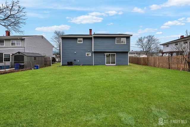 rear view of house with central AC unit and a lawn