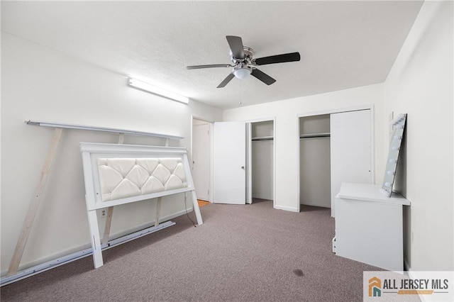 unfurnished bedroom with multiple closets, carpet flooring, a textured ceiling, and a ceiling fan