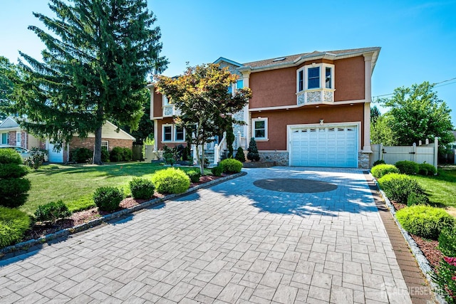 view of front of house with a garage, stone siding, decorative driveway, stucco siding, and a front yard