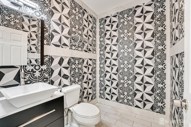 bathroom featuring tile walls, vanity, and toilet