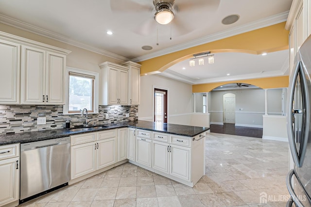 kitchen with arched walkways, appliances with stainless steel finishes, a ceiling fan, a sink, and a peninsula