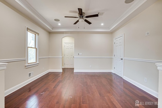 empty room with ornamental molding, wood-type flooring, a raised ceiling, and visible vents