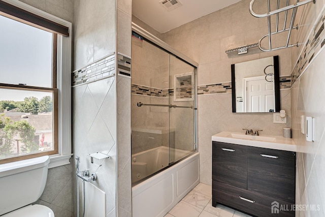 bathroom with toilet, visible vents, vanity, tile walls, and marble finish floor