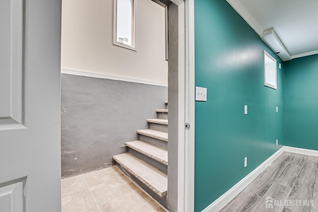 stairway with ornamental molding, baseboards, and wood finished floors