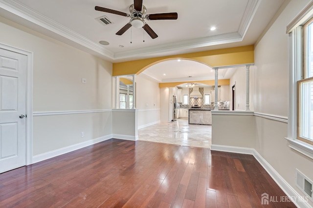 spare room with baseboards, visible vents, wood finished floors, and ornamental molding