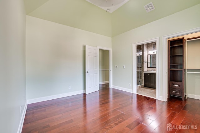 unfurnished bedroom featuring connected bathroom, wood finished floors, visible vents, and baseboards