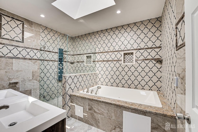 full bathroom with a sink, walk in shower, a garden tub, and tile walls