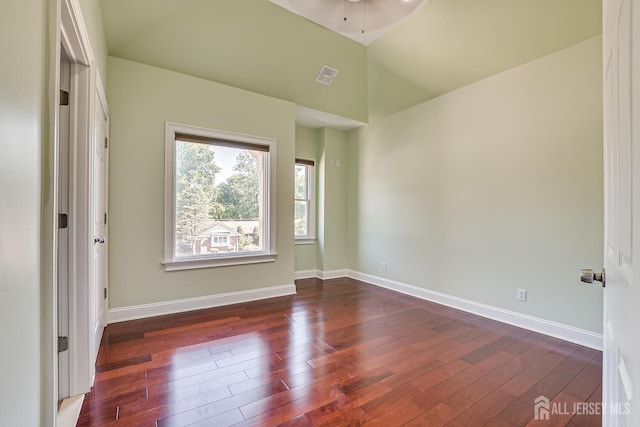 interior space featuring vaulted ceiling, wood finished floors, visible vents, and baseboards