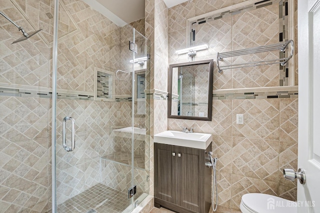 full bathroom featuring toilet, a shower stall, tile walls, and vanity