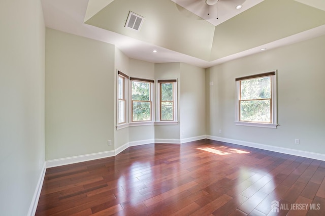 unfurnished room with dark wood-style flooring, visible vents, and a healthy amount of sunlight