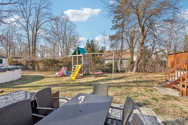 view of yard with a fenced in pool, stairway, outdoor dining space, and a playground